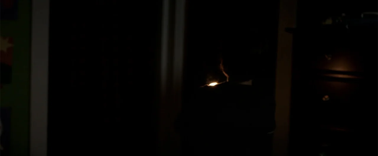 Lights Out (2016) movie still: medium — A very dark interior room with almost all detail obscured by heavy shadow. A person stands facing away from…