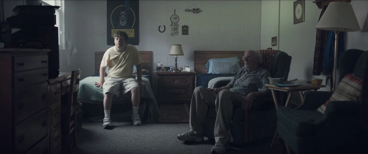 The Peanut Butter Falcon (2019) movie still: wide — A spare bedroom features two twin beds with simple bedding and white cinder block walls. A…