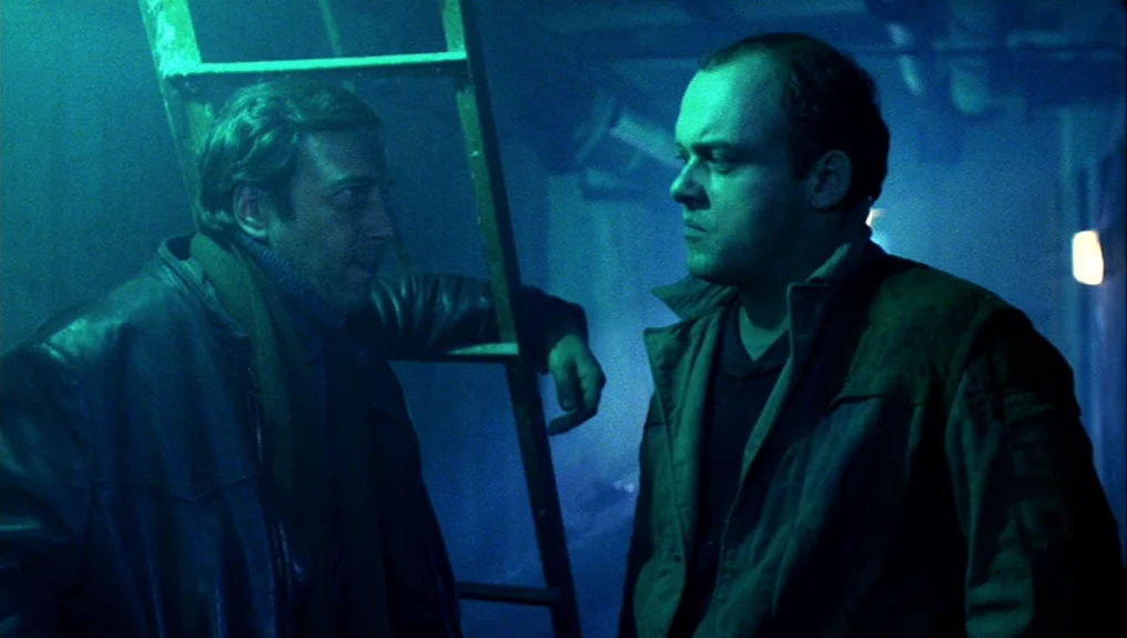O-Bi, O-Ba: The End of Civilization (1985) movie still: medium — A dark subterranean space is filled with thick haze and a wooden ladder. Two men…