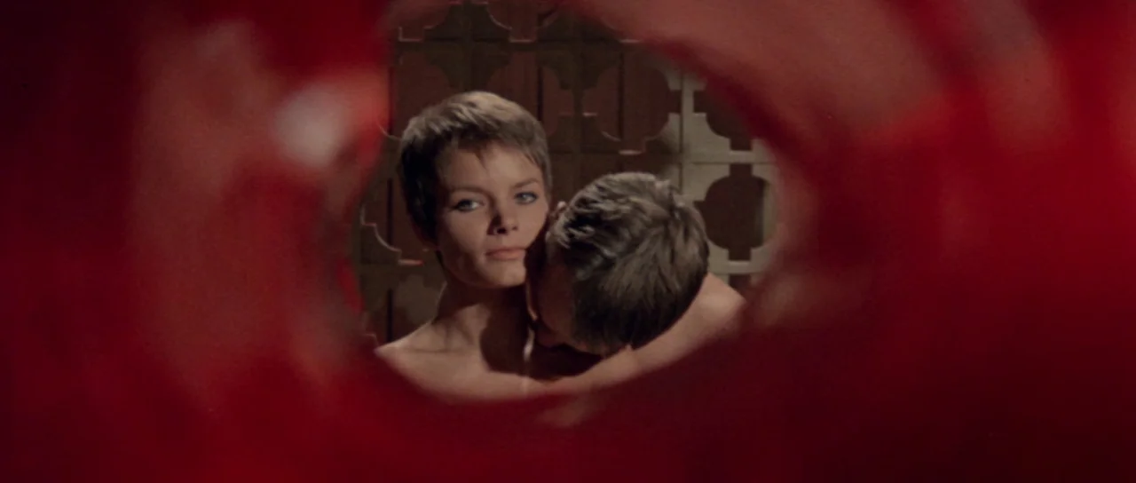 Orgasmo (1969) movie still: medium — Two individuals are captured through a blurred, circular red foreground element. The woman faces the camera…