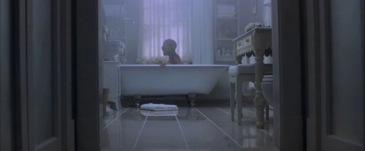 What Lies Beneath (2000) movie still: wide — A spacious bathroom features a clawfoot tub positioned beneath a large window covered with curtains. A…