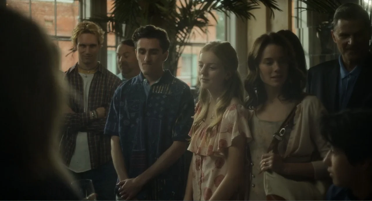 May December (2023) movie still: medium — A group of young adults stands in a sunlit room near a window. They appear to be attending a gathering or…