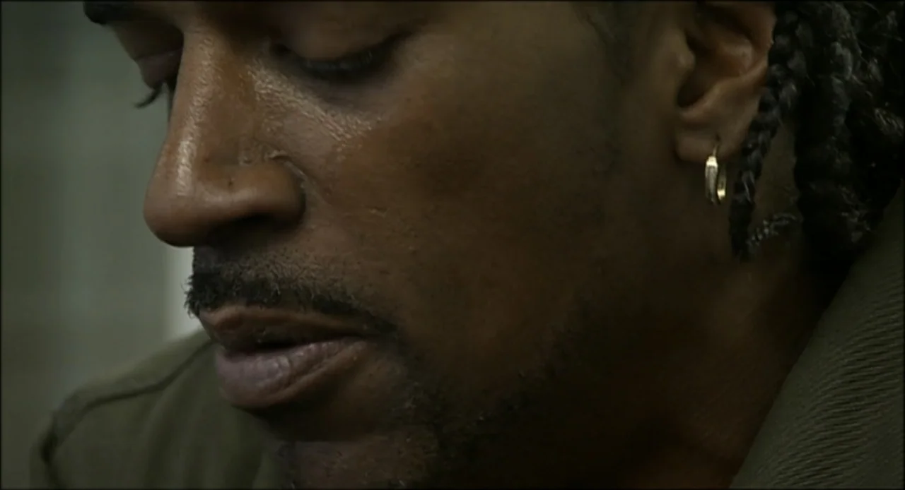 Hard as Nails (2001) movie still: closeup — A dark indoor space provides a neutral background for the close-up portrait. A man with braids and…