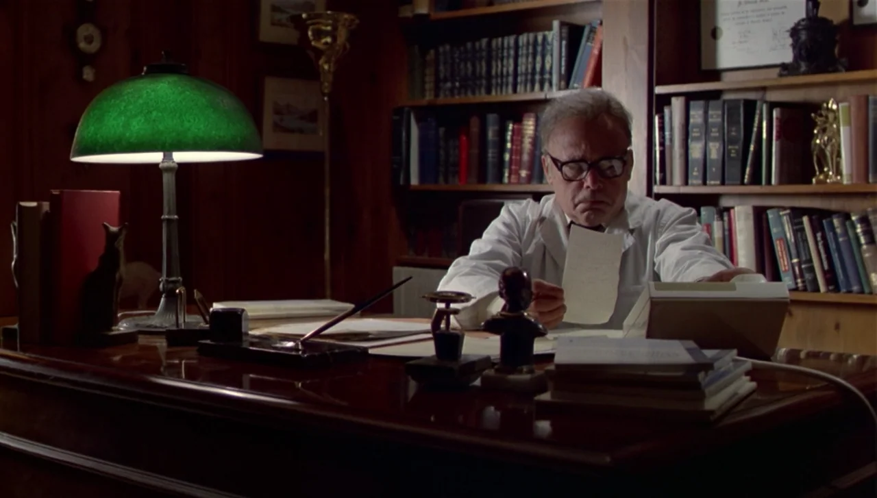 The Dead Zone (1983) movie still: medium — A wood-paneled office features floor-to-ceiling bookshelves packed with vintage leather-bound volumes. An…