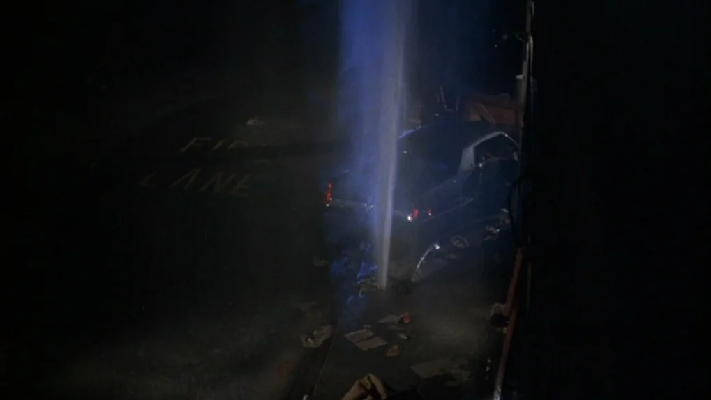 Mean Streets (1973) movie still: wide — A dark, empty parking lot at night shows a vertical stream of water spraying upwards. The words FIRE LANE…