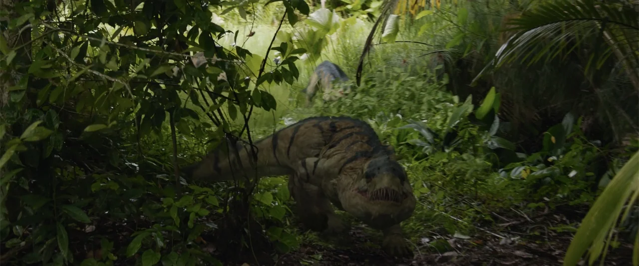 Meg 2: The Trench (2023) movie still: medium — A dense, humid jungle environment with thick vegetation and deep shadows between tangled branches. A…