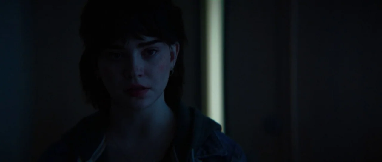 The Boogeyman (2023) movie still: closeup — A dimly lit indoor space features a subject standing against a dark wall. A vertical light source behind…