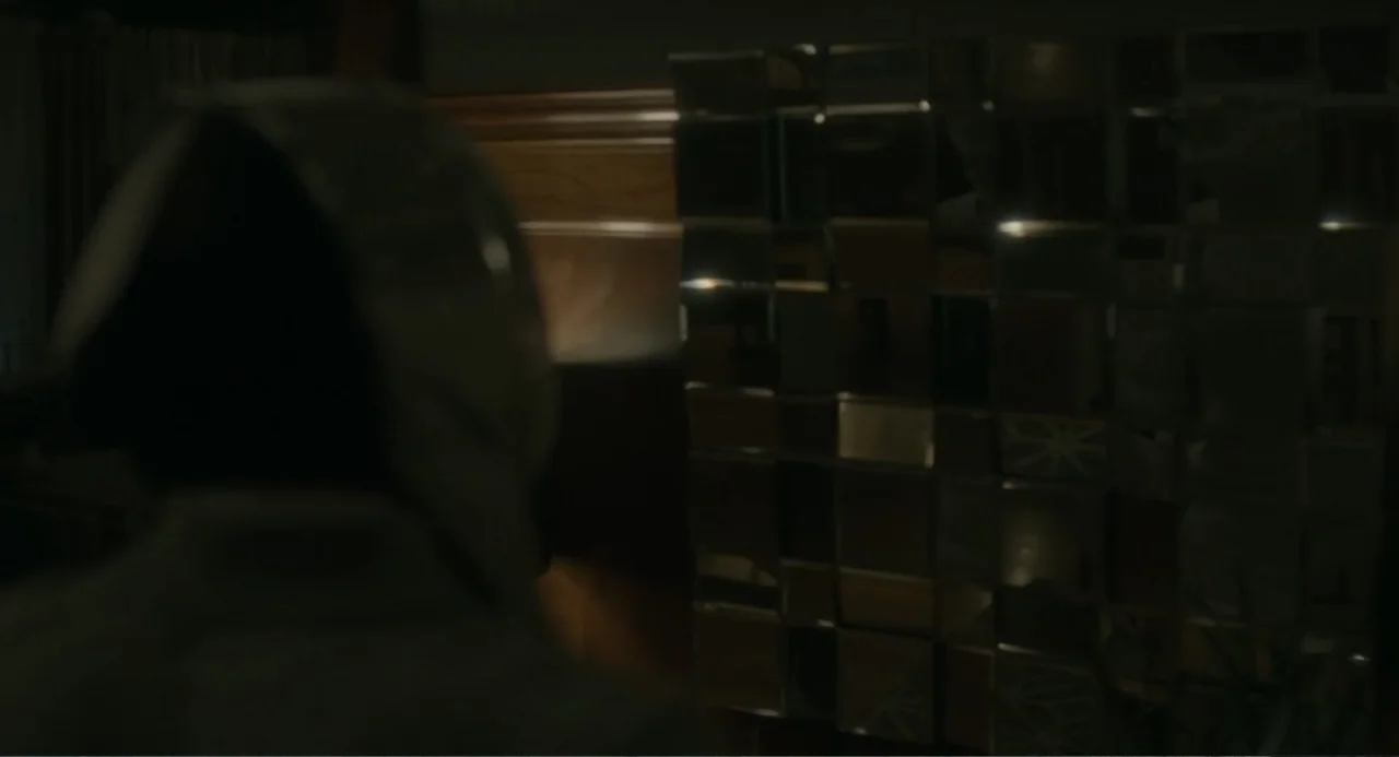 Orphan: First Kill (2022) movie still: medium — A dark bedroom features a tall cabinet surfaced with dozens of reflective square mirrors. A person…