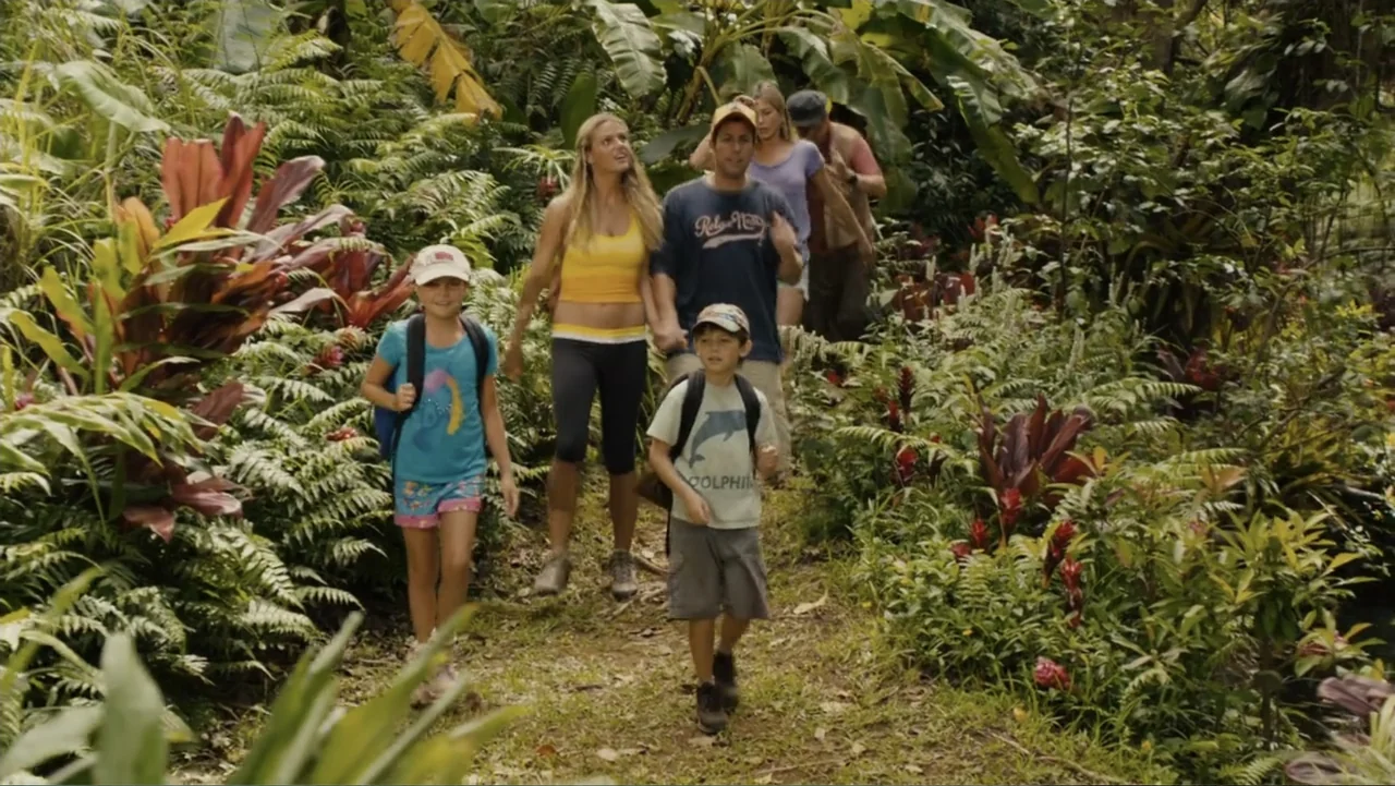 Just Go with It (2011) movie still: fullbody — A group of people walks along a narrow dirt path through a dense jungle. Lush tropical ferns, large…