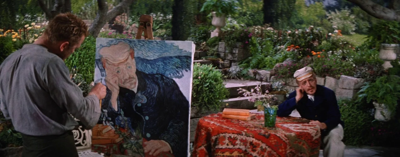 Lust For Life (1956) movie still: wide — A lush outdoor garden features a man painting on an easel near a table. The seated man wears a cap and sits…
