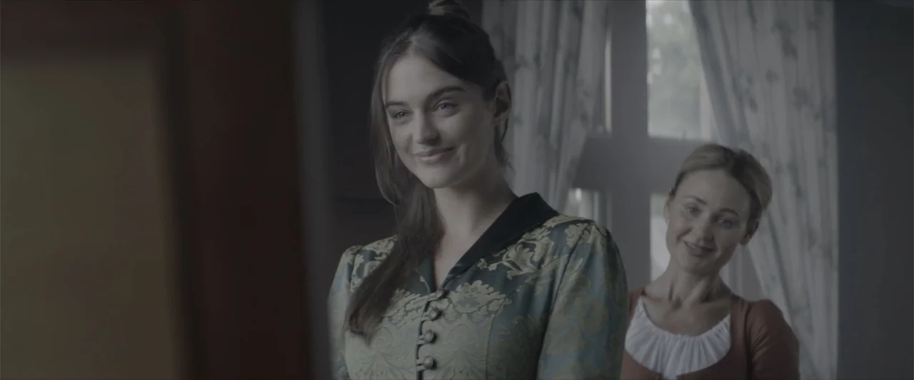Cinderella's Curse (2024) movie still: medium — An 1800s bedroom features patterned curtains and a mirror hanging against a dark wall. A woman in a…