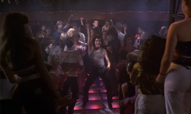 Spetters (1980) movie still: fullbody — A crowded discotheque features people dancing on an illuminated grid of floor tiles. A man in the center…