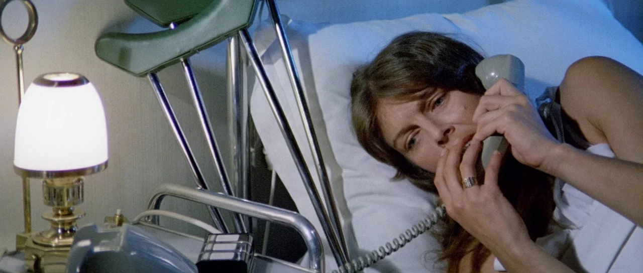 What Have They Done To Your Daughters? (1974) movie still: medium — A hospital bed with chrome railings is situated in a dimly lit room at night. A…
