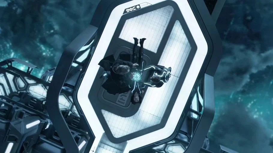 TRON: Legacy (2010) movie still: wide — A high-tech digital environment with stark white geometric structures and deep blue dark zones. Three people…