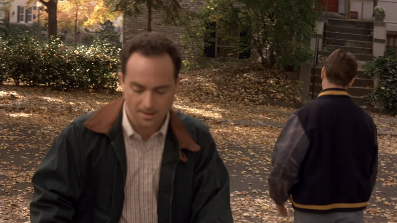 A Few Good Men (1992) movie still: medium — A suburban residential street covered in autumn leaves with a house in the background. Two men walk in…