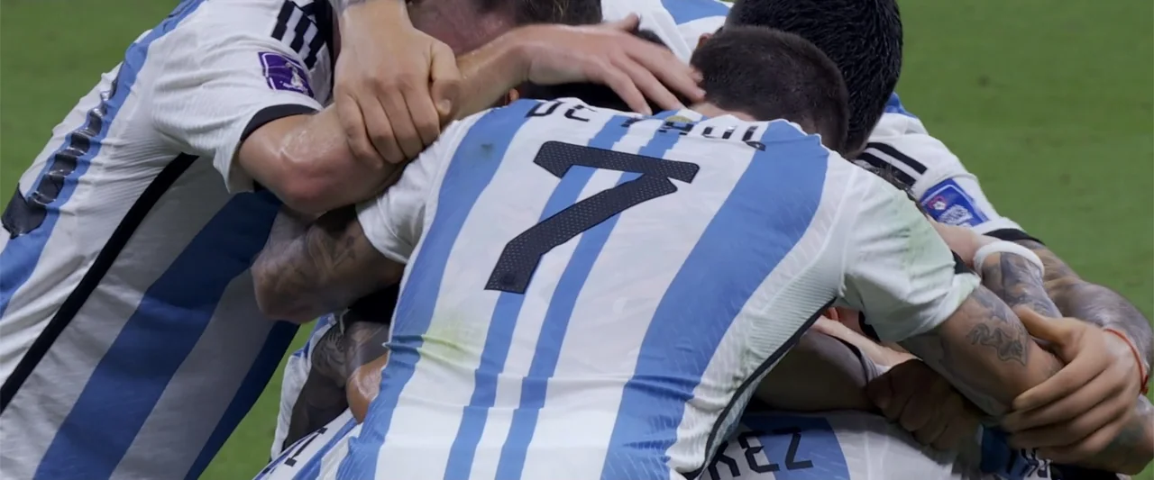 I Choose to Believe (2023) movie still: medium — A group of professional soccer players wearing striped jerseys gather on a green field. The…