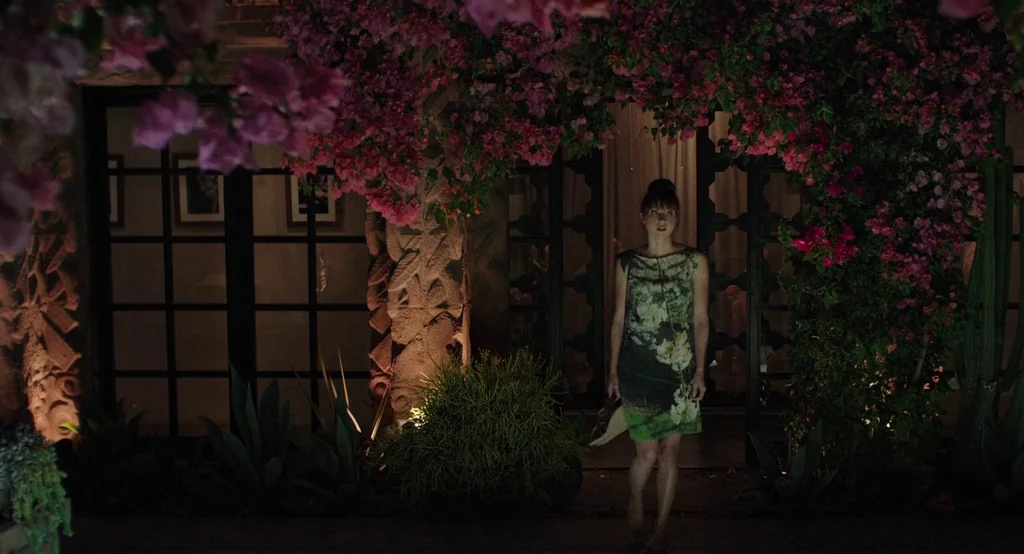 Ruby Sparks (2012) movie still: fullbody — A dimly lit courtyard features dark carved stonework and dense, blooming magenta bougainvillea overhead.…