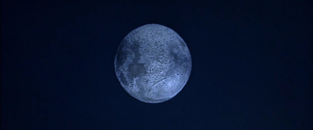 The Fearless Vampire Killers (1967) movie still: closeup — A full moon with detailed craters sits against a dark, featureless night background. The…