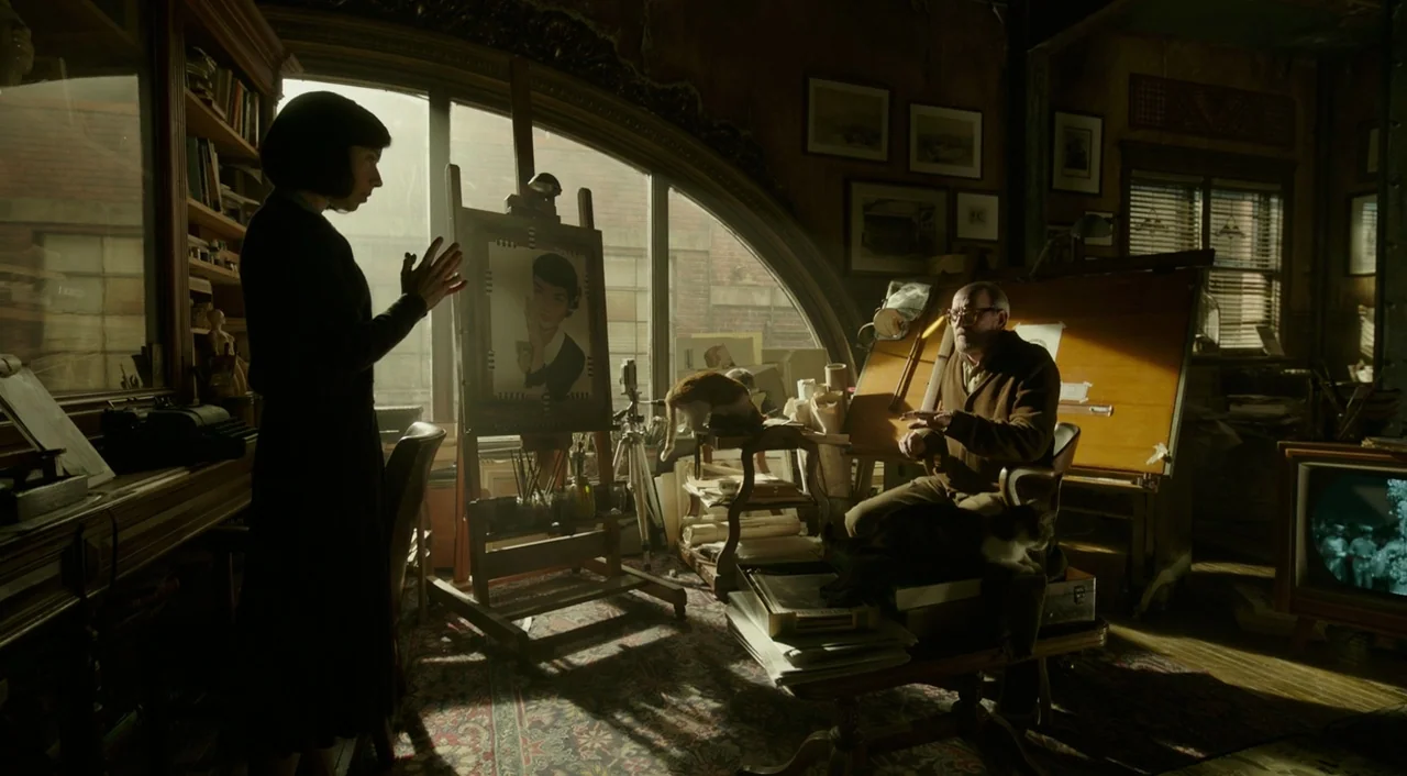 The Shape of Water (2017) movie still: wide — A cluttered 1940s workspace features a large arched window, easels, and scattered papers. A woman in…