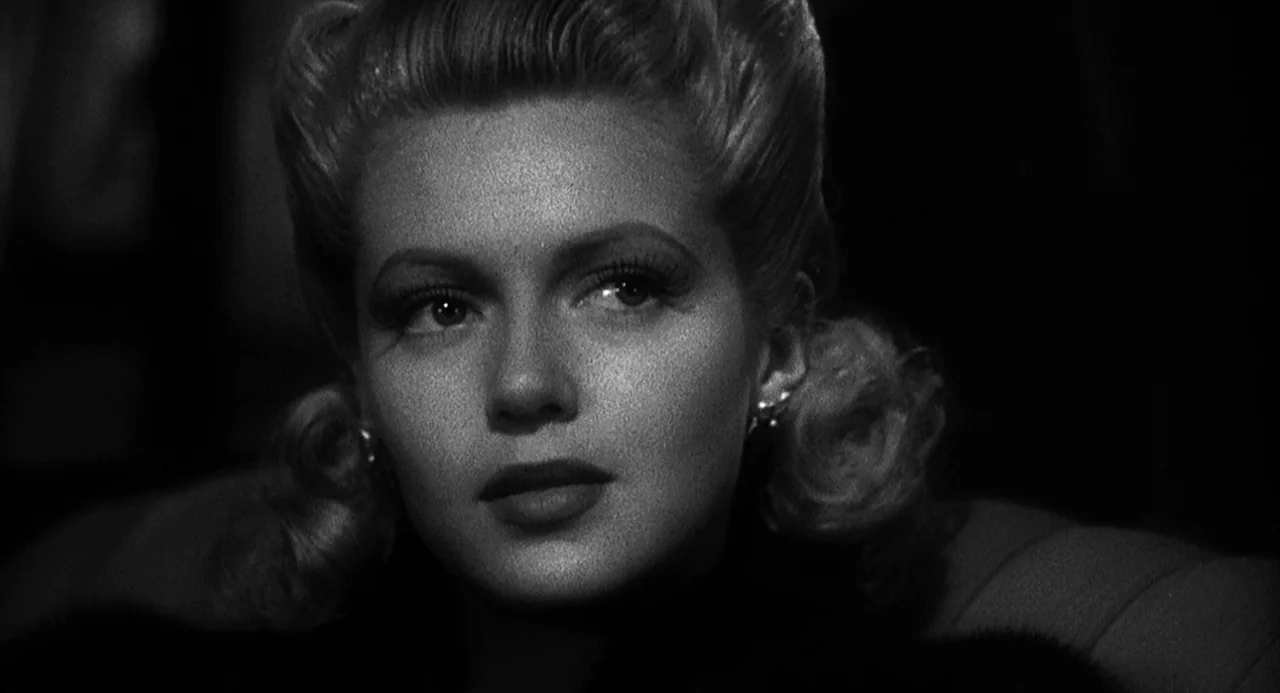 Dead Men Don’t Wear Plaid (1982) movie still: closeup — A dark, dimly lit lounge provides a shadowy backdrop for a woman's face. The woman sits…