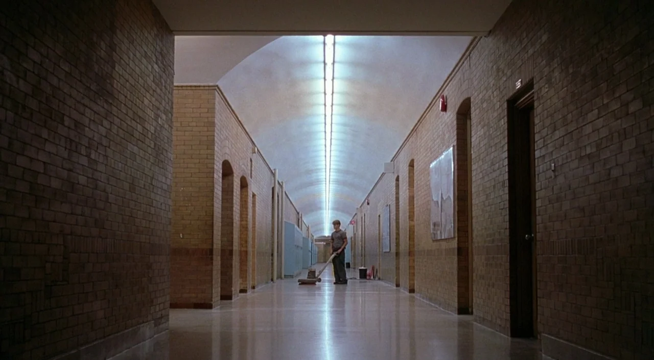 Good Will Hunting (1997) movie still: wide — A long, symmetrical brick school hallway features a vaulted ceiling and recurring arched doorways. A…