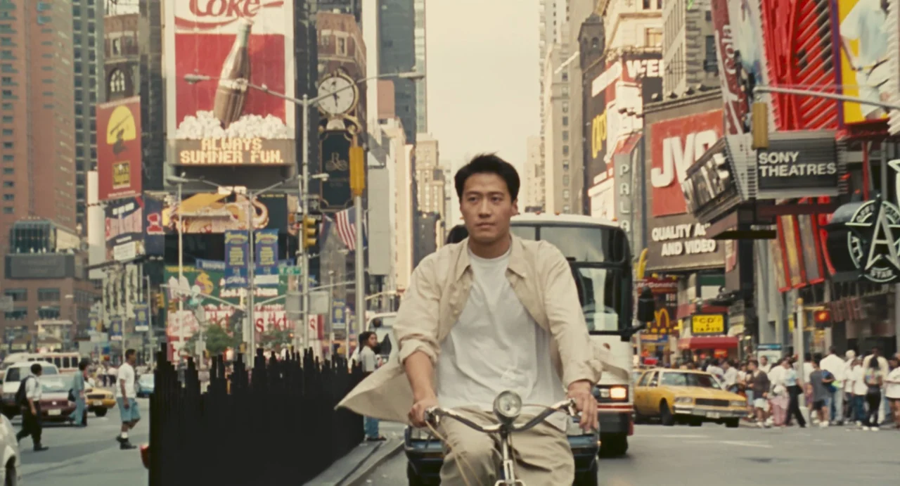 Comrades: Almost A Love Story (1996) movie still: medium — A man rides a bicycle through a busy intersection in Times Square, New York. Large…