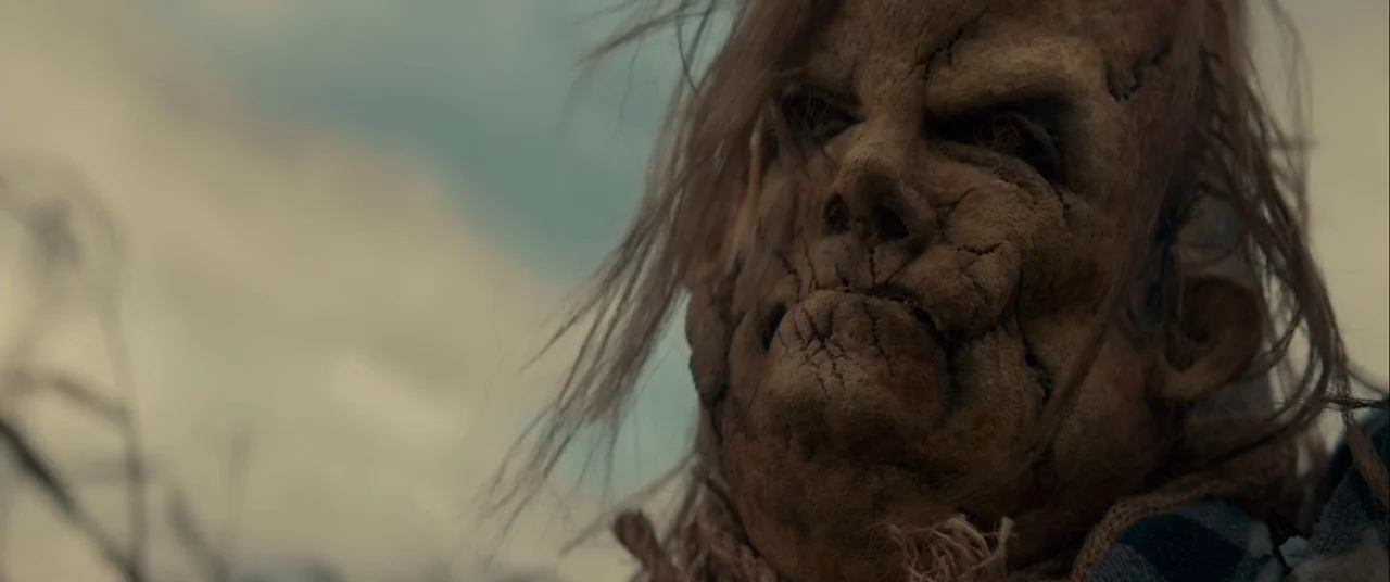Scary Stories to Tell in the Dark (2019) movie still: closeup — An outdoor location with blurred dry vegetation under a bright, overcast sky. A…