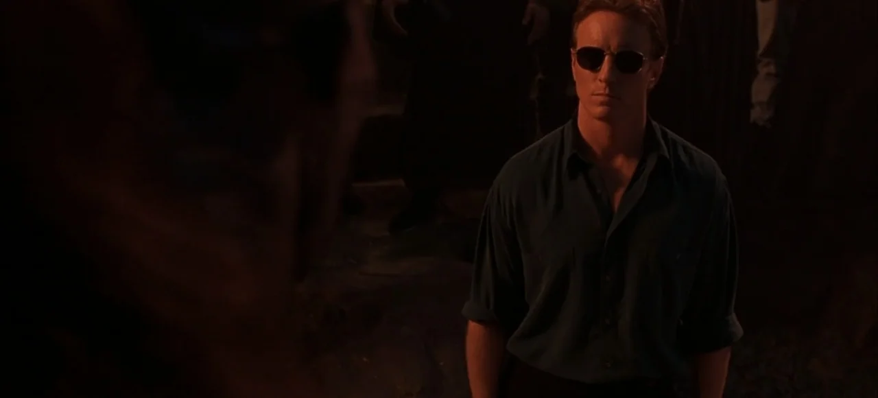 Mortal Kombat (2021) movie still: medium — A dimly lit interior space with a person in the foreground silhouette. A man stands in the background…