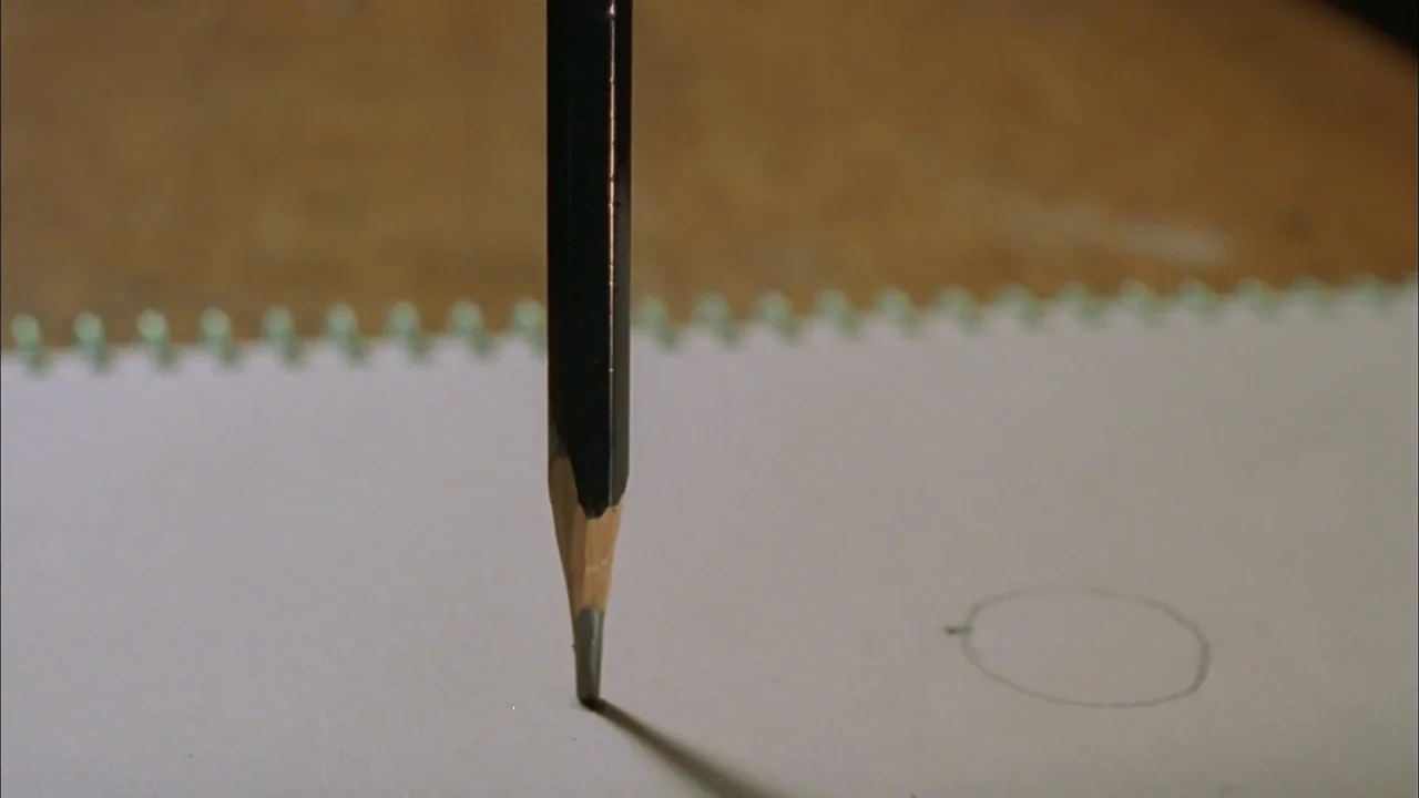 Whispering Corridors (1998) movie still: closeup — A dark pencil is positioned vertically against a white piece of spiral notebook paper. The pencil…