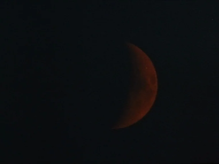Salome (1972) movie still: wide — A dark night sky frames a glowing, reddish lunar crescent. The celestial object is positioned to the right of the…