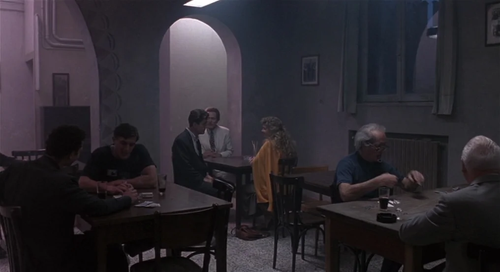 The Comfort of Strangers (1990) movie still: wide — A dimly lit room features arched stone architecture and several people at wooden tables.…