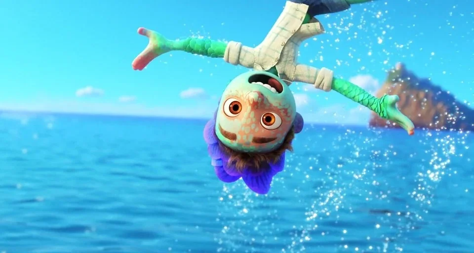 Luca (2021) movie still: medium — An open blue ocean with a small rocky island in the distance. A green-skinned creature with purple hair falls…