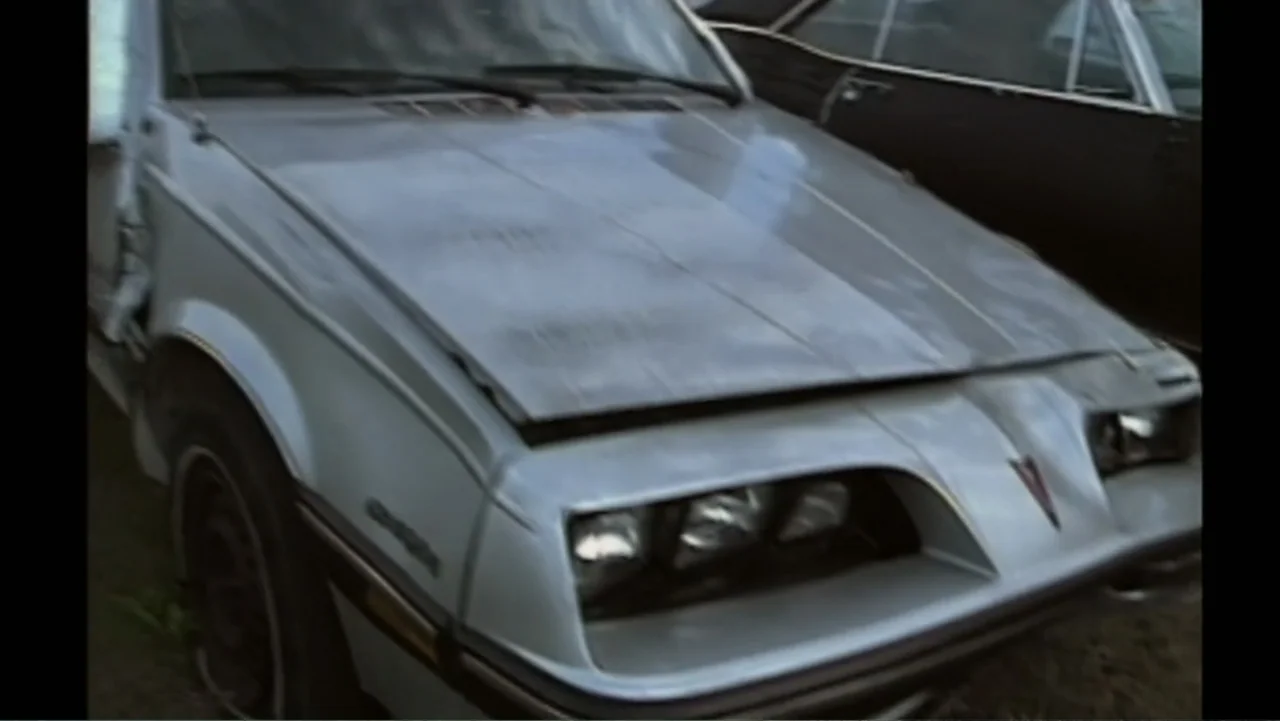Aileen Wuornos : Mind of a Monster (2020) movie still: medium — A silver Pontiac Sunbird sits parked in a field with weathered exterior paint…