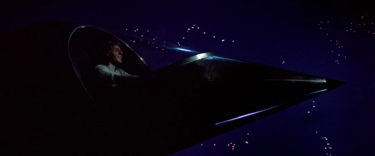 Lisztomania (1975) movie still: medium — A dark space exterior showing a sleek black spacecraft navigating against a starry background. A man with…