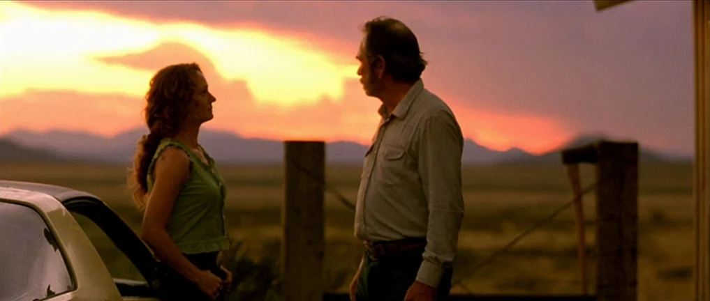 The Three Burials of Melquiades Estrada (2005) movie still: medium — An open desert landscape at dusk with distant mountains under a glowing orange…