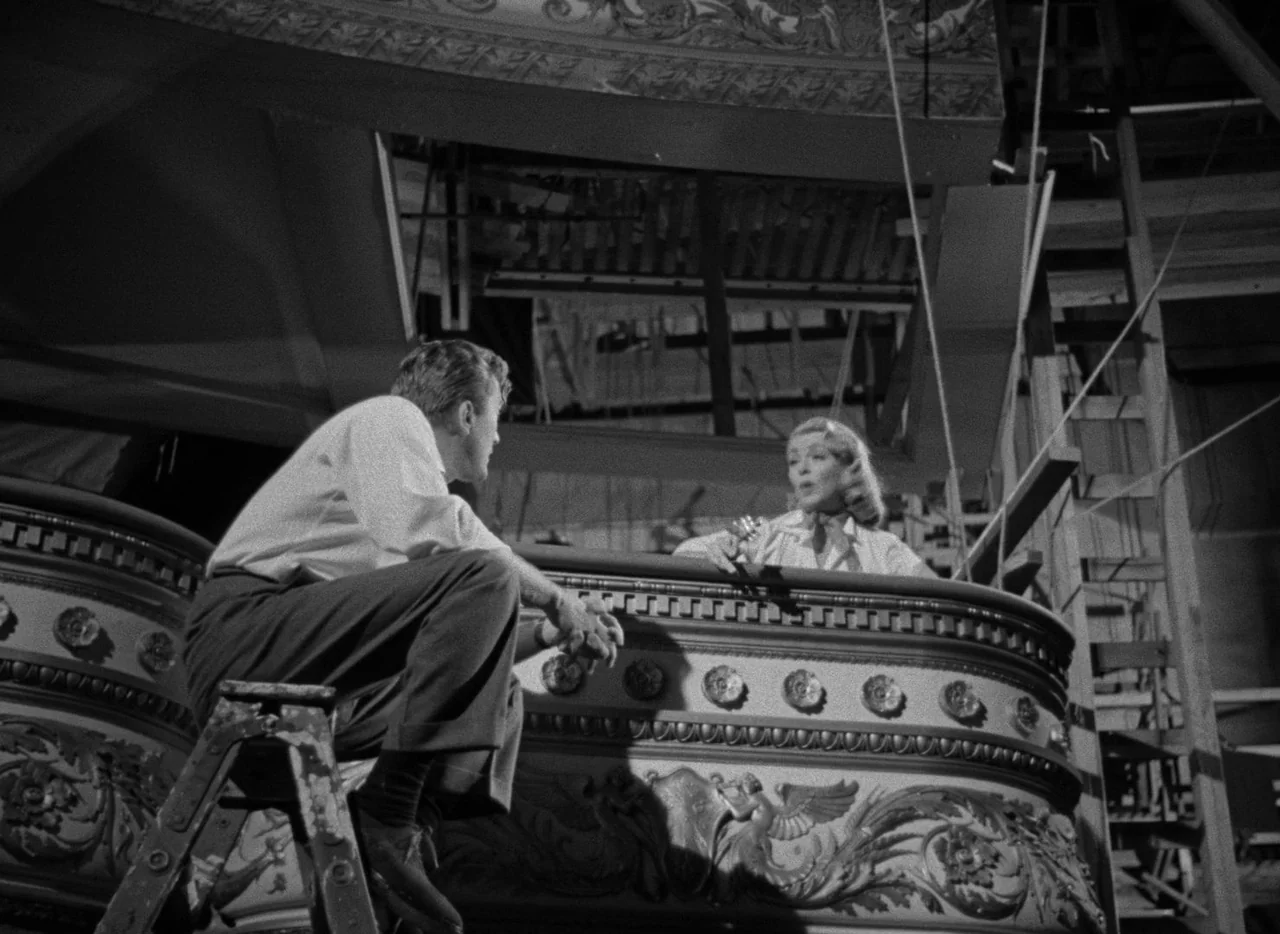 The Bad and the Beautiful (1952) movie still: medium — A ornate theater balcony with carved decorations and a wooden step ladder. A man sits on a…