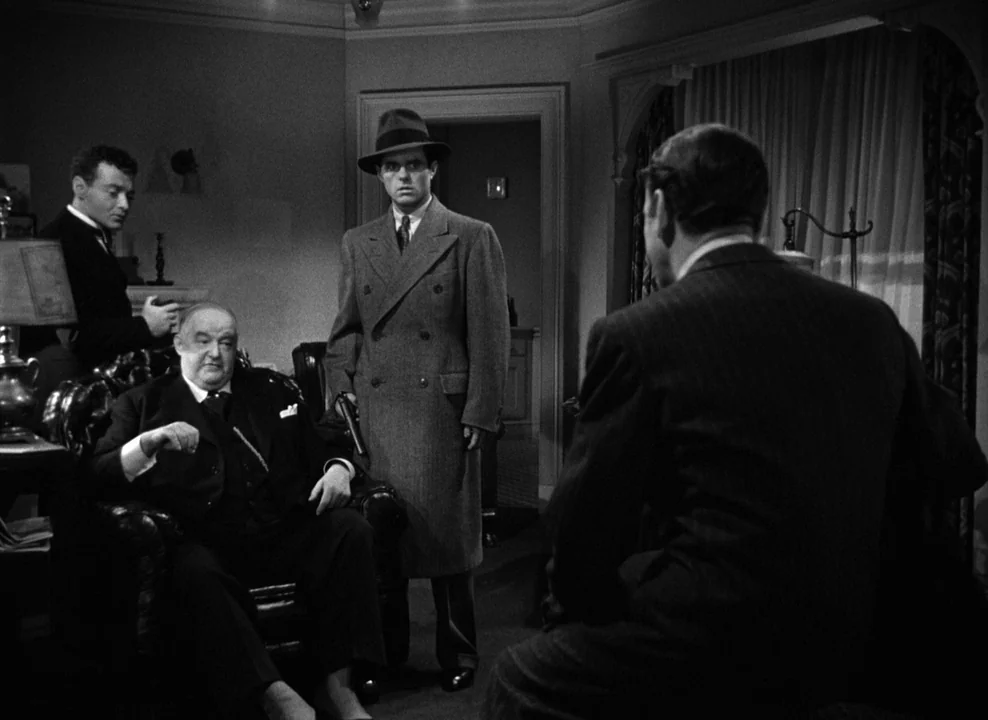 The Maltese Falcon (1941) movie still: medium — A dimly lit room with heavy furniture and drawn curtains in the background. Four men are positioned…