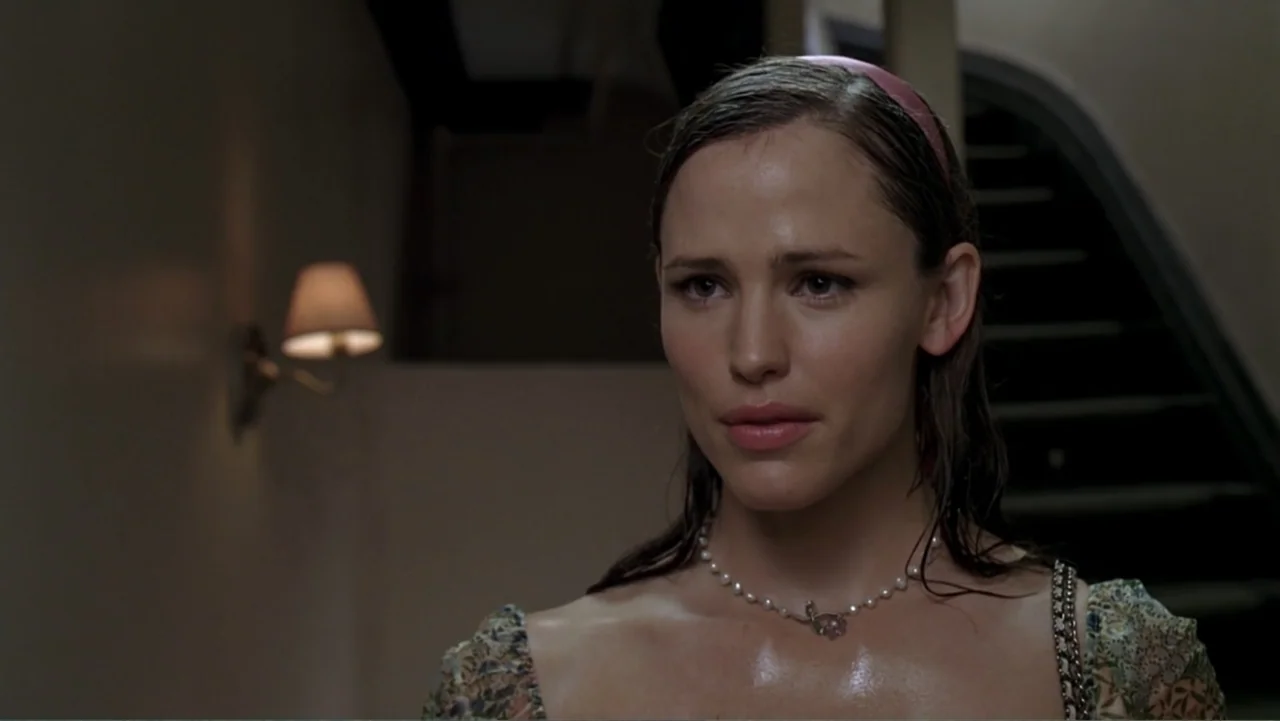 13 Going on 30 (2004) movie still: closeup — A dimly lit indoor stairwell features a beige wall with a wall lamp fixture. A woman stands in the…