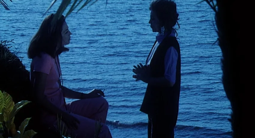 5 Dolls for an August Moon (1970) movie still: medium — Two women interact near the water's edge under a clear night sky. They are surrounded by…