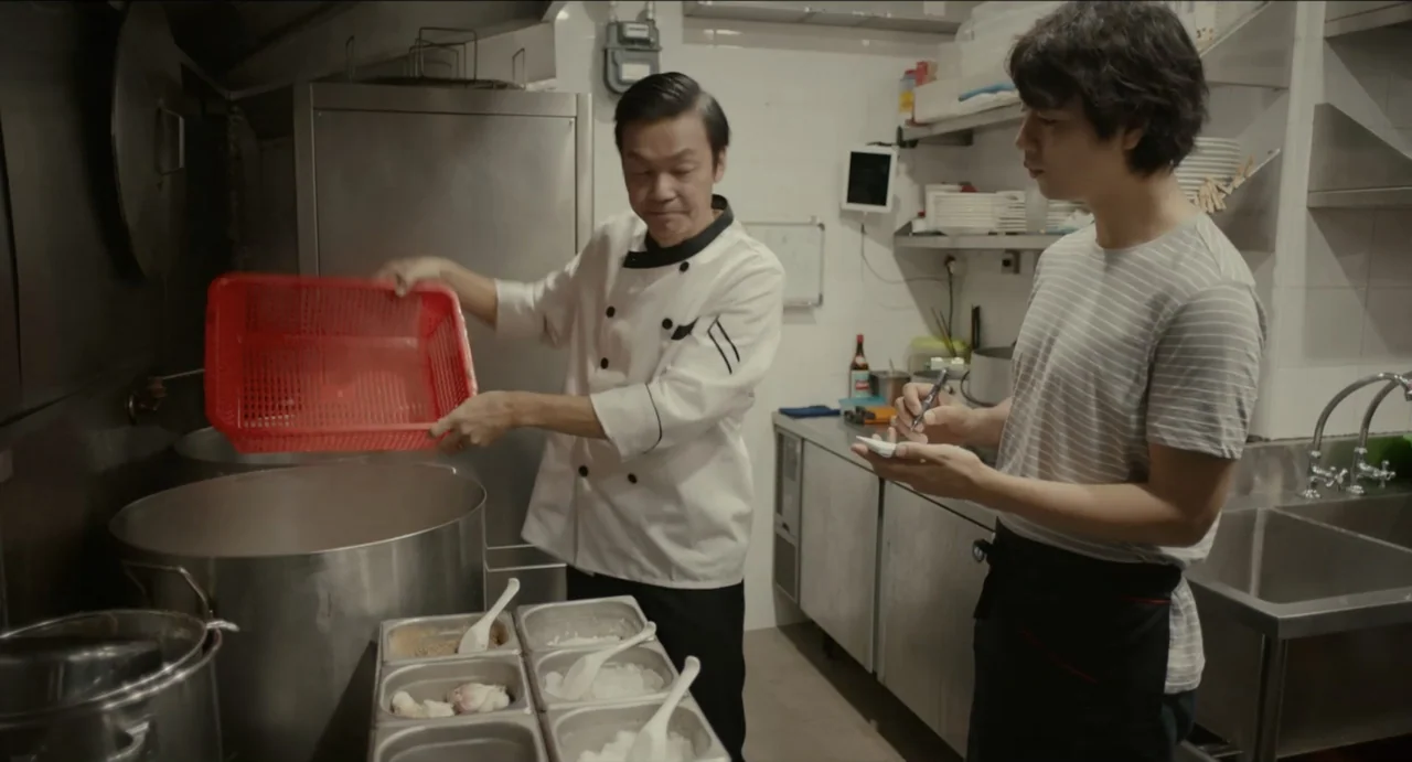 Ramen Shop (2018) movie still: medium — A professional kitchen features stainless steel surfaces, large stockpots, and various food prep containers.…