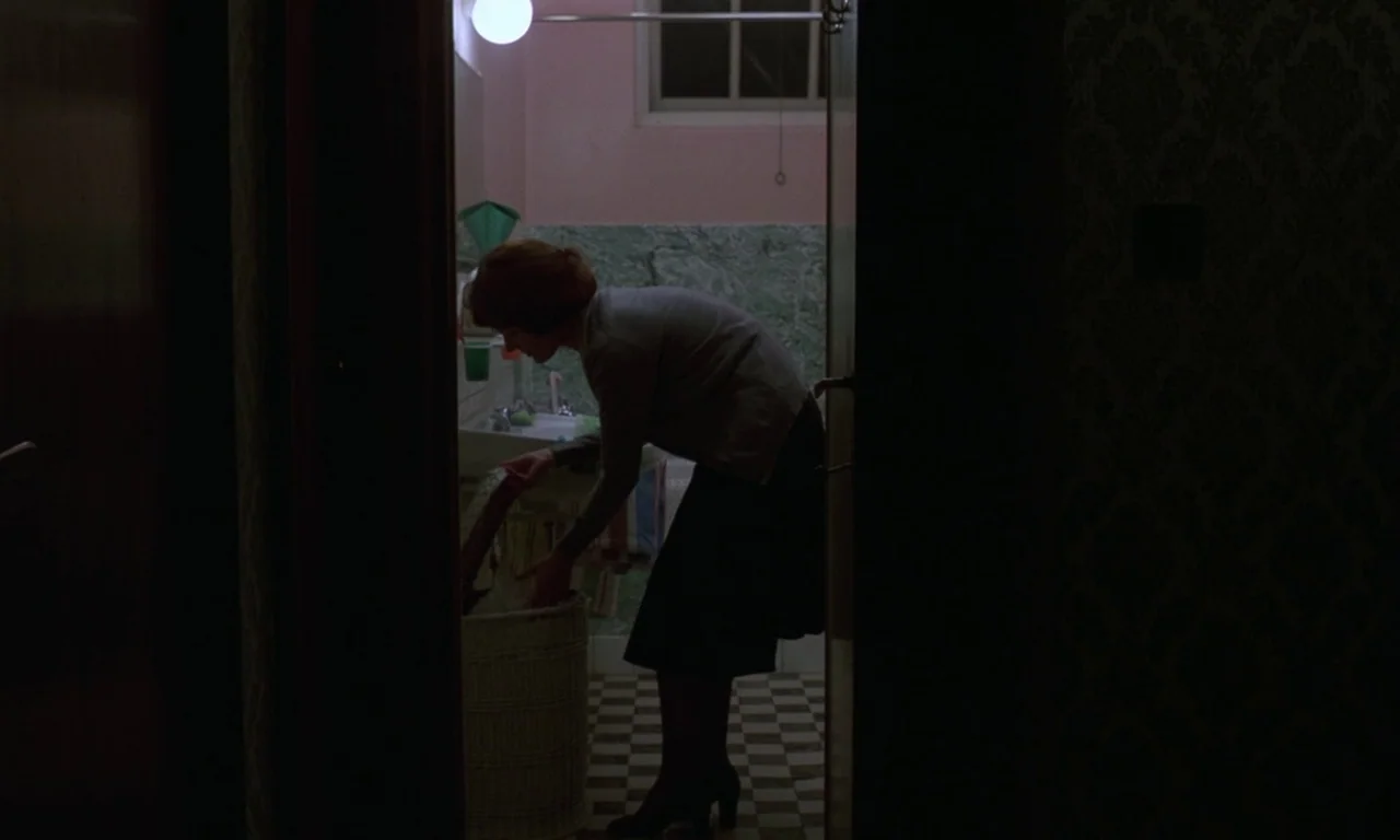 Jeanne Dielman, 23, quai du commerce, 1080 Bruxelles (1975) movie still: medium — A view through a darkened doorway into a small bathroom with tiled…
