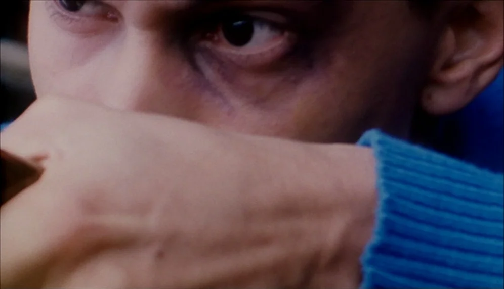 Nenette et Boni (1996) movie still: closeup — A close-up captures a man's eyes and the upper portion of his face. He is wearing a blue sweater and…