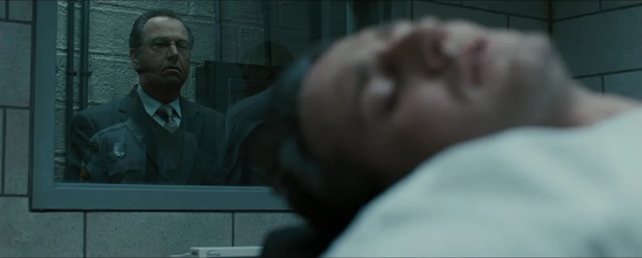 Law Abiding Citizen (2009) movie still: medium — An austere room features gray concrete block walls and a large glass viewing window. A man in a…