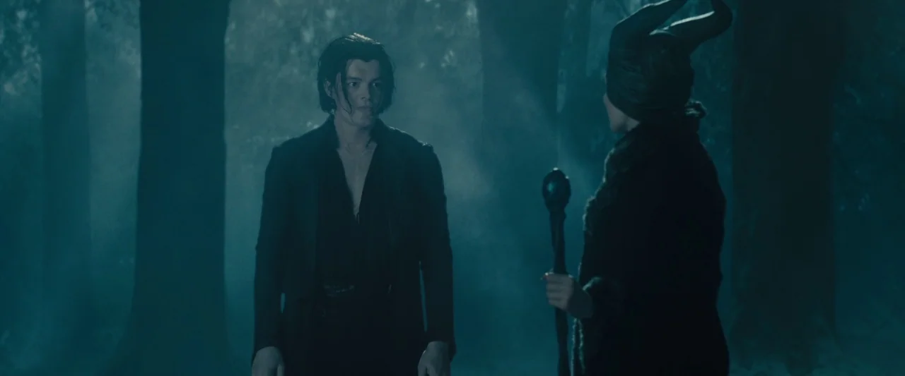 Maleficent (2014) movie still: medium — A dark, misty forest floor with tall trees shrouded in thick, cool-toned fog. A young man stands opposite a…