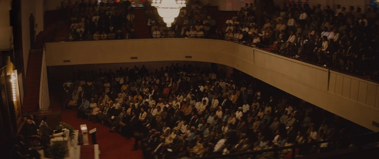 Selma (2014) movie still: wide — A large church interior features a balcony filled with a seated congregation. A speaker stands at the front pulpit…