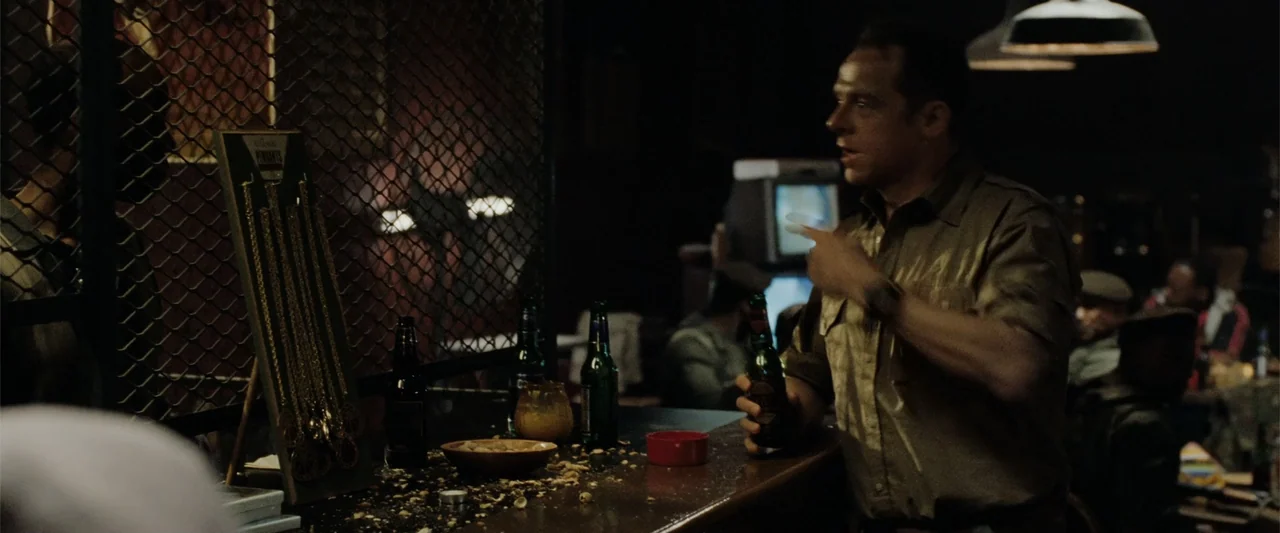 Hector and the Search for Happiness (2014) movie still: medium — A dark, dimly lit dive bar features a wooden counter cluttered with bottles and…