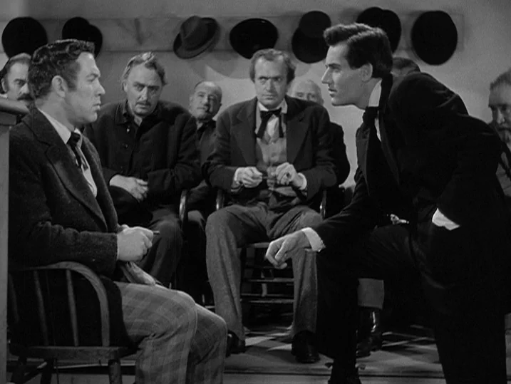 Young Mr. Lincoln (1939) movie still: medium — A group of men sit in a sparse room with hats hanging on the wall. A man in a dark suit leans in to…