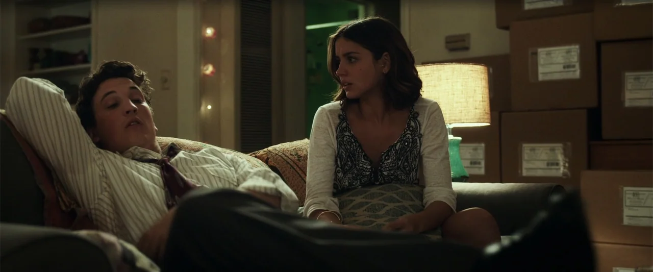 War Dogs (2016) movie still: medium — An interior living space filled with cardboard boxes stacked in the background. A young man and woman sit…