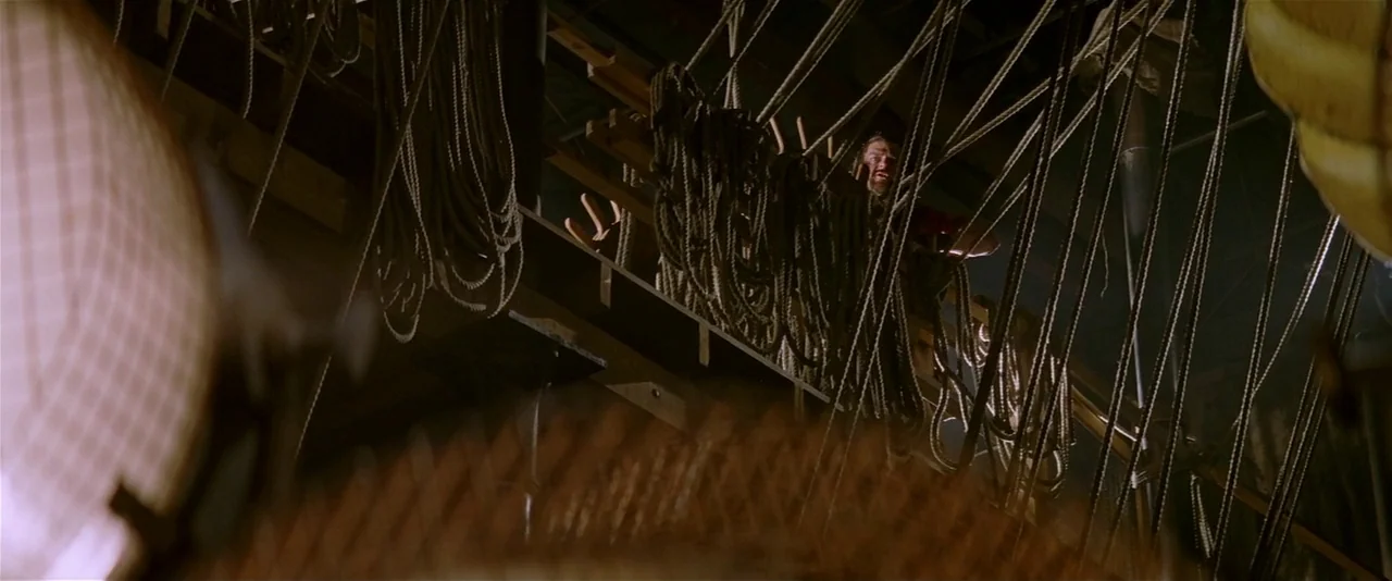 The Phantom of the Opera (2004) movie still: wide — A dark, industrial interior structure filled with vertical and diagonal hanging ropes. A man…