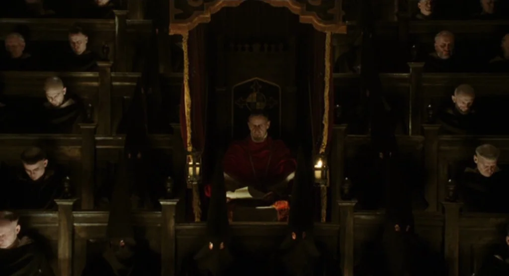 The Fountain (2006) movie still: wide — A dark, wood-paneled assembly hall features tiered seating occupied by figures in hooded robes. A…